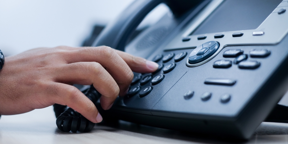 Business user dialing VoIP phone demonstrating how VoIP 911 compliance emergency calling works 