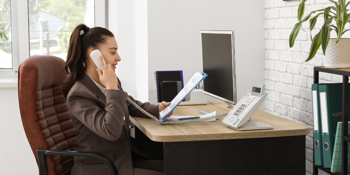 Office employee answering desk phone illustrating CCaaS vs VoIP communication in everyday business operations